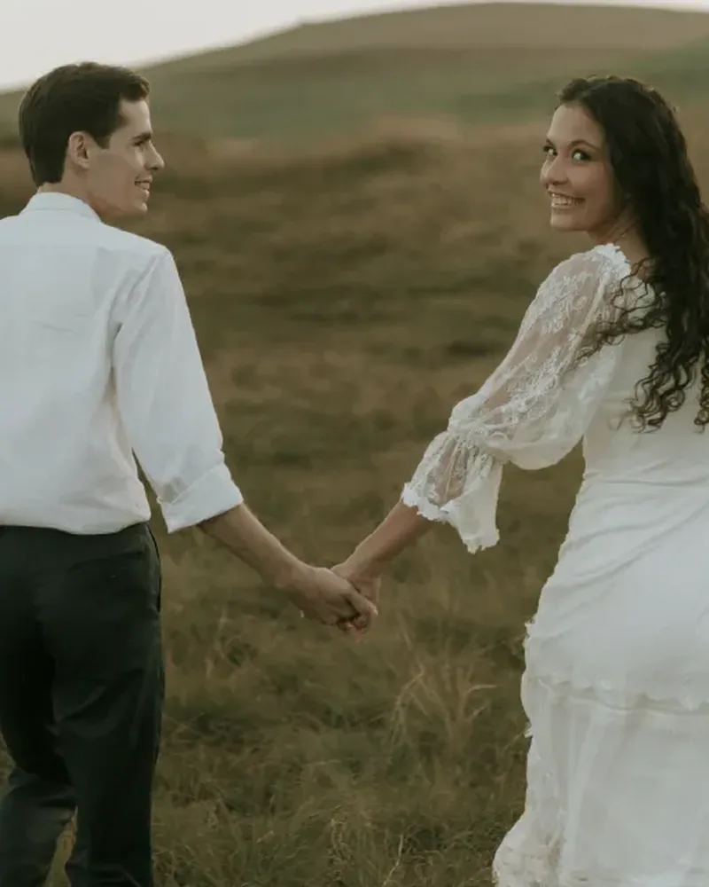Oliver und Marie laufen Hand in Hand durch die Dünenhügel